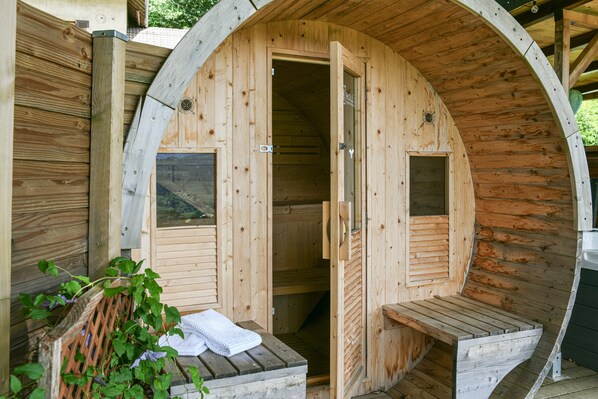 A wooden sauna with an arched roof, a bench, and a small window.