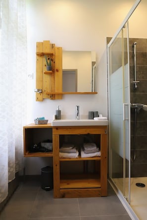 Une salle de bain avec un meuble-lavabo en bois, une cabine de douche en verre et un miroir au-dessus du lavabo.