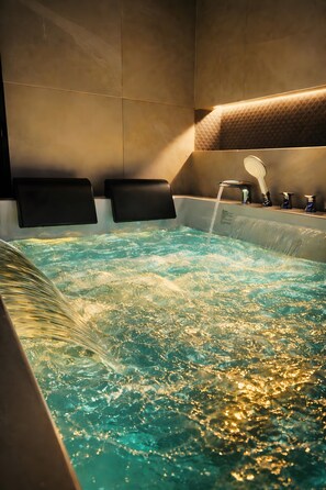 A hot tub with water jets, a showerhead, and a tiled wall. - Exclusive Suite Room with Mountain View, Wi-Fi, and Air Conditioning (Palermo)