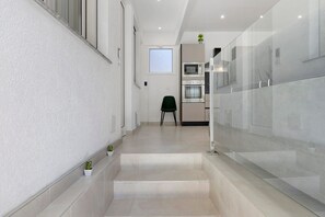 Eine moderne Küche mit Einbauofen und Mikrowelle, ein kleiner grüner Stuhl und ein Fenster mit Blick.