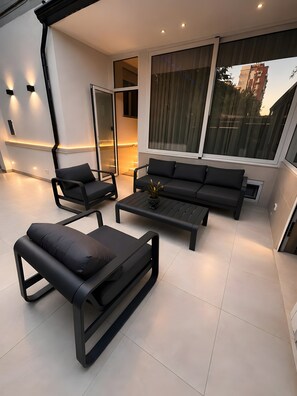 Un espace de vie extérieur moderne comprenant un canapé, des fauteuils et une table basse.