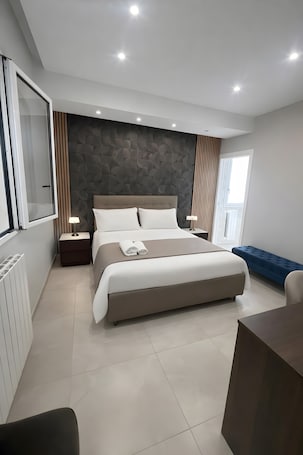 A modern bedroom with a large bed, bedside tables, a blue bench, and a view of the outdoors.. Room 'Golden' with Mountain View, Wi-Fi and Air Conditioning
