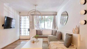 A modern living room with a sofa, a coffee table, a TV, and large windows. - Breathtaking house with private rooftop in Condesa (Ciudad de México)