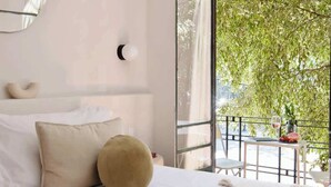 A bedroom with a bed, pillows, a bedside table with a glass of wine, and a view of a balcony with greenery. - Breathtaking house with private rooftop in Condesa (Ciudad de México)