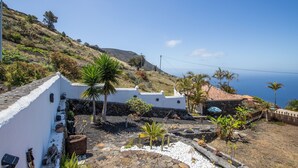 A coastal property with white walls, a stone roof, and a view of the sea. - Apartment 'Casa' with Sea View, Wi-Fi and Air Conditioning (Los Quemados)