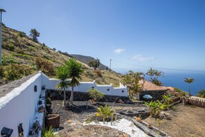 A coastal property with white walls, a stone roof, and a view of the sea.