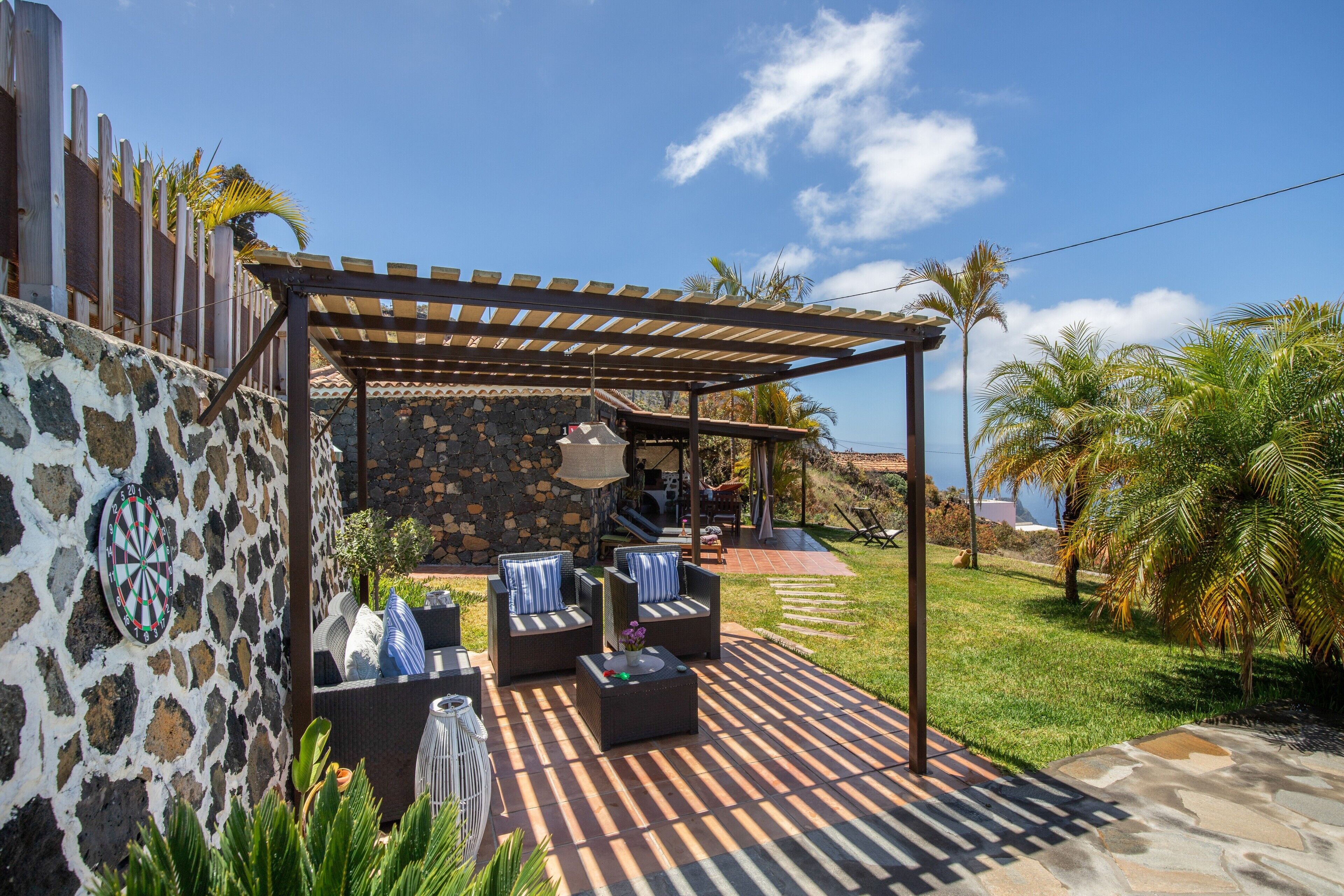 Eine Terrasse mit Sitzgelegenheit im Freien, einer Steinmauer und einem Pergola.