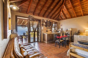 A cozy interior with a wooden ceiling, a dining area, a kitchen, and a seating area with a view.