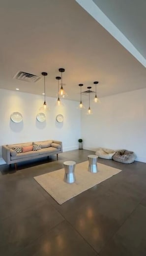 Una sala moderna con un sofá, dos mesas de centro metálicas e iluminación colgante.