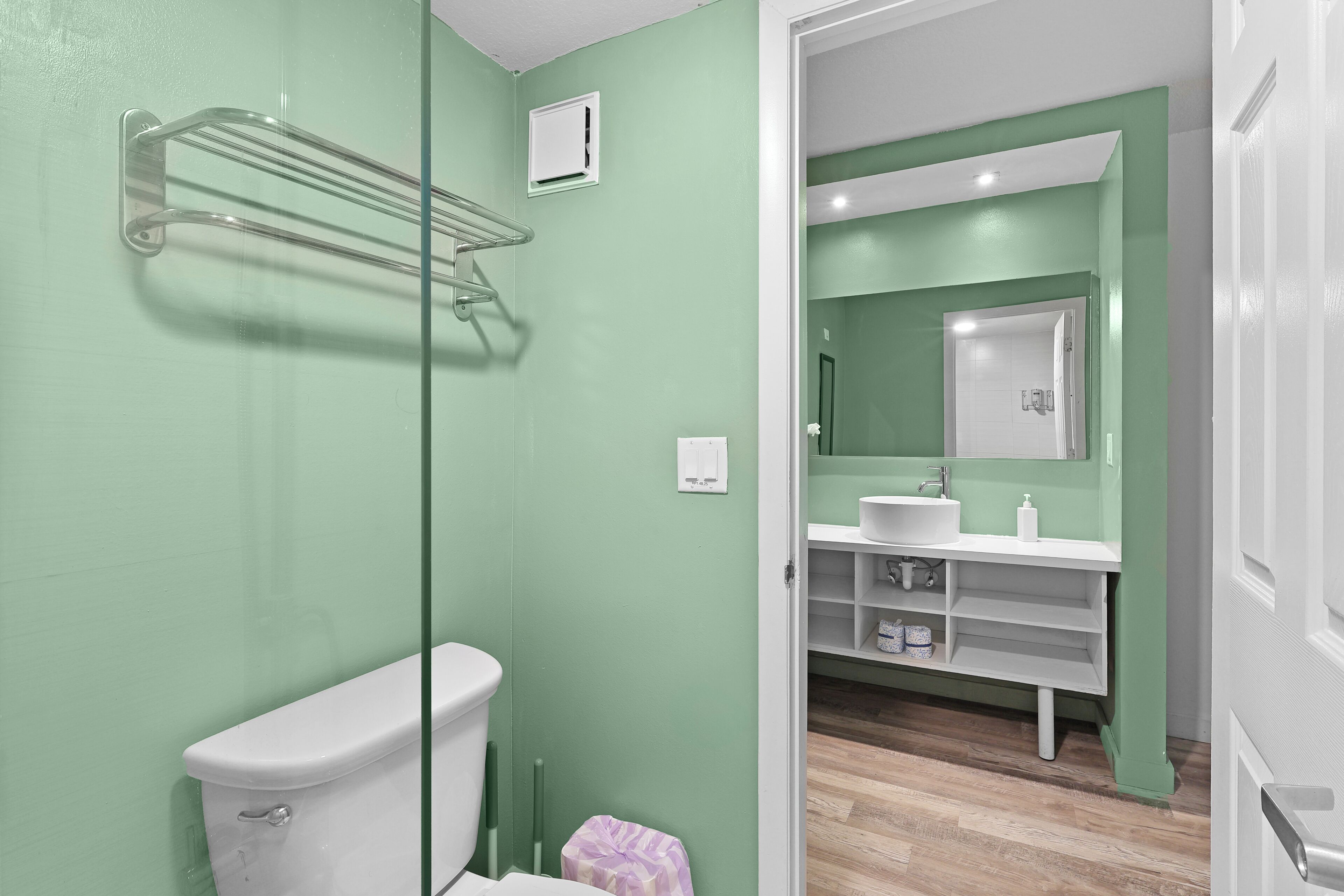 A bathroom with a toilet, a glass shower enclosure, a sink with a mirror, and a white vanity.