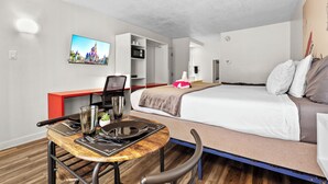 Pieni hotellihuone, jossa on sänky, työpöytä, tuoli, televisio ja mikroaaltouuni.