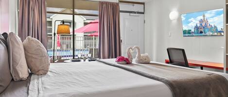 A hotel room with a bed, a desk, a chair, a TV, and a window with curtains.