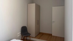 Een compacte, moderne kamer met een kledingkast, een stoel en een deur.