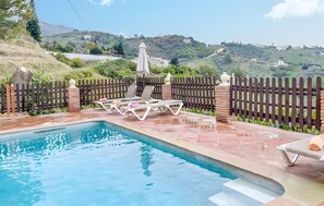 A swimming pool with lounge chairs and a wooden fence, surrounded by greenery and hills in the background. - Country House 'Villa El Tejo' with Sea Views, Wi-Fi, and Air Conditioning (Frigiliana)