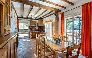 A kitchen with wooden cabinets, a glass-top table, and a brick oven. - Country House 'Villa El Tejo' with Sea Views, Wi-Fi, and Air Conditioning (Frigiliana)