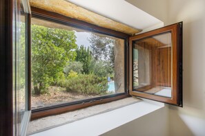 Una ventana con vistas a zonas verdes y un edificio al fondo.