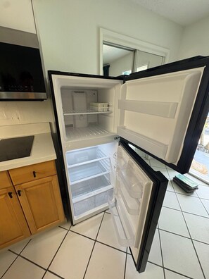 Eine Küche mit Einbaukühlschrank, Holzschränken und Fliesenboden.