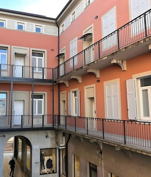 Un edificio a più piani con balconi, finestre con persiane e un percorso pedonale.
