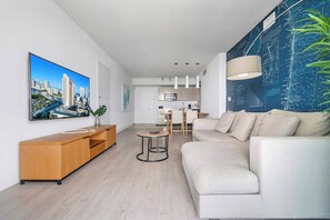 A modern living room with a sofa, a coffee table, and a TV mounted on the wall. - Beachside Haven | Scenic Views | Modern (Hallandale Beach)