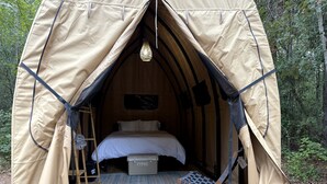 Une tente équipée d’un lit, d’une échelle et d’un luminaire suspendu.