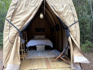 A tent with a bed, a ladder, and a hanging light fixture.