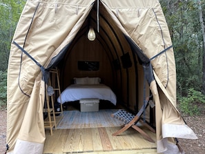 A tent with a bed, a ladder, and a hanging light fixture.