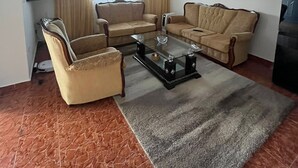 Un saló amb un sofà, una butaca, una taula de centre, televisió i obra d'art a la paret.