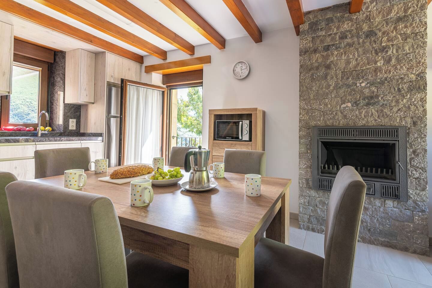 Un comedor con una mesa de madera, sillas y una chimenea de piedra.