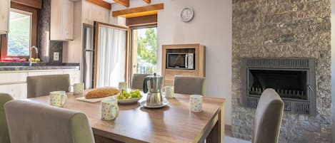 Een eetruimte met een houten tafel, stoelen en een stenen openhaard.