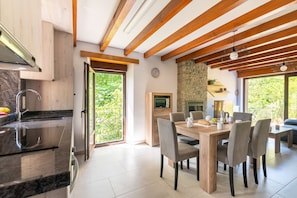 A modern kitchen with a large island, wooden beams, and a dining area with a table and chairs.
