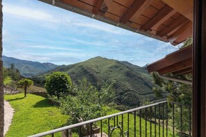 A balcony with a view of green hills and a clear sky.