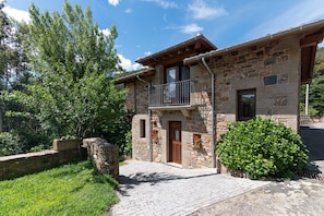 A stone building with a balcony, a wooden door, and a window.
