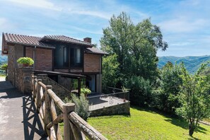 Une maison à deux étages avec une façade en pierre, un balcon et une vue sur le paysage environnant.