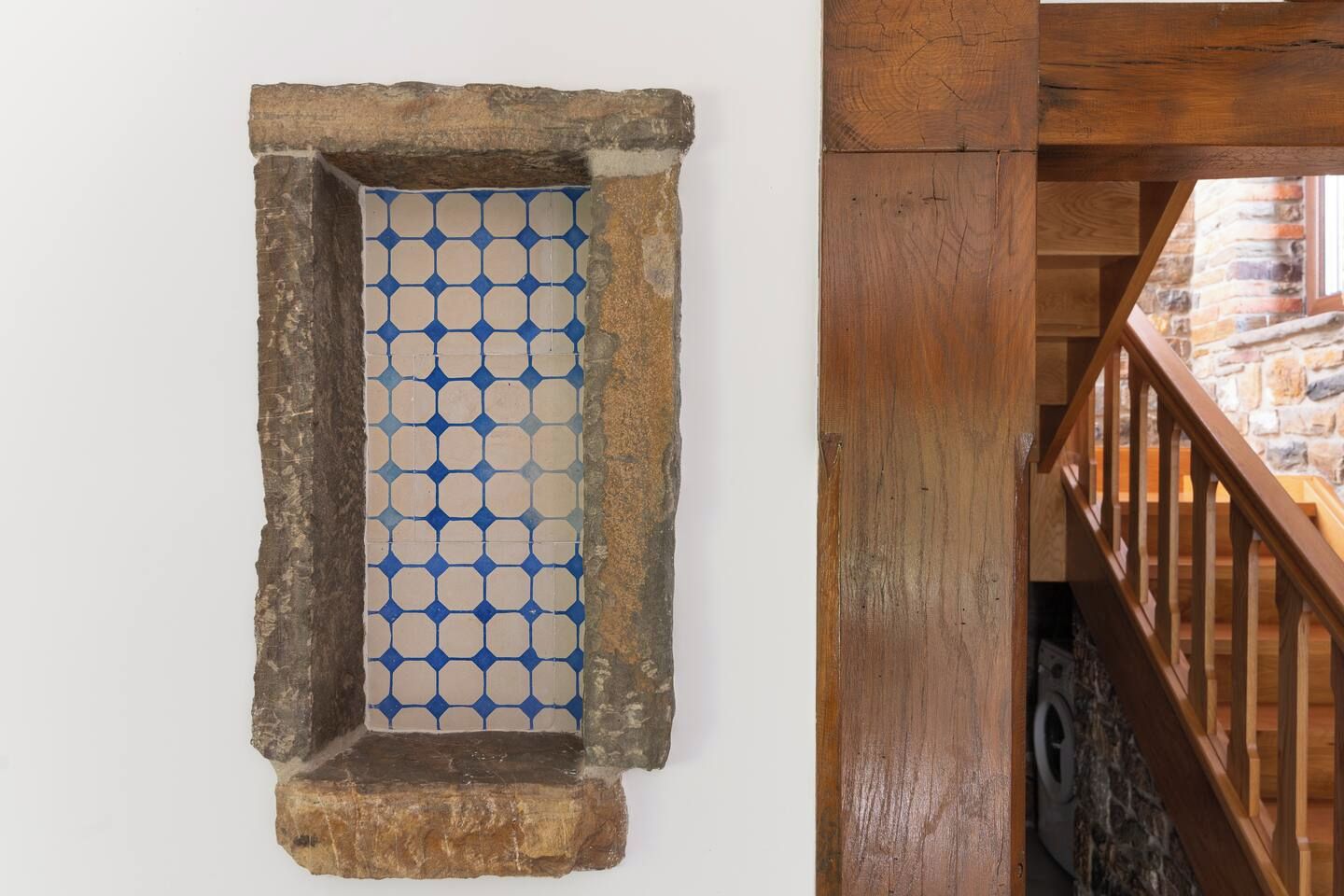Una ventana con marco de piedra y un diseño geométrico azul y blanco.