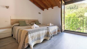 A bedroom with two beds, a wooden ceiling, and a balcony with a metal railing. - Tranquillity by Fidalsa (Cabezón de Liébana)
