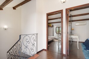 A staircase with a metal railing, a bedroom with a bed and a desk, and a bathroom with a mirror and a towel rack.