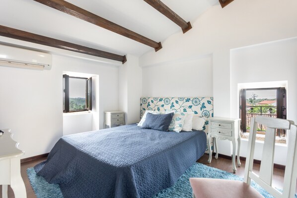 A bedroom with a bed, nightstands, a window, and a view of the outside.