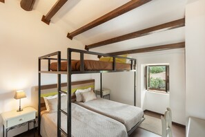 A bunk bed room with a window, a bedside table, and a chair.