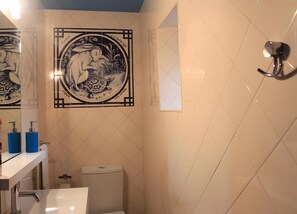 Ein Badezimmer mit Toilette, Waschbecken und einer dekorativen Wandfliese mit einer Schildkröte.