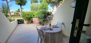 A patio with a round table, chairs, and a small garden view. - ✨La Romantique Villa (Le Grau du Roi)