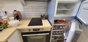 Eine Küche mit Arbeitsplatte, Schneidebrett, Kühlschrank mit Regalen und Backofen.