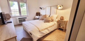 A bedroom with a bed, bedside table, lamp, and a window. - ✨La Romantique Villa (Le Grau du Roi)