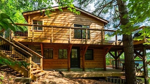 A wooden cabin with a balcony, a staircase, and a deck.