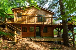 A wooden cabin with a balcony, a staircase, and a deck. - Lake It Easy | On Portage Lake (Parry Sound District)