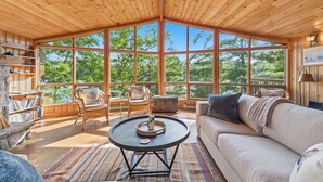 A spacious room with large windows, a round coffee table, a sofa, and a fireplace.