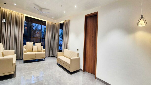 A modern living room with two beige sofas, a ceiling fan, and a wooden door. - Standard Twin Roompalette Fairmont Gonda (Gonda)