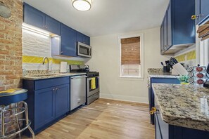 Une cuisine avec des armoires bleues, une cuisinière en acier inoxydable, un four à micro-ondes et un plancher en bois.