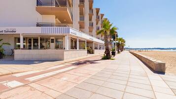 A beachfront hotel with a covered walkway, palm trees, and a clear view of the ocean.