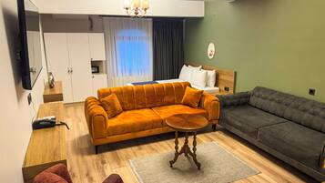 Una sala de estar moderna con un sofá, un sillón rojo, una mesa de centro y un televisor montado en la pared.