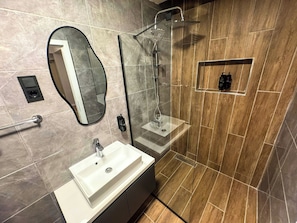 A modern bathroom with a vanity, a mirror, a shower, and a toilet. - Fethibey Otel (Bartın)